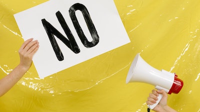 Image of hand holding card that says "No" facing a megaphone
